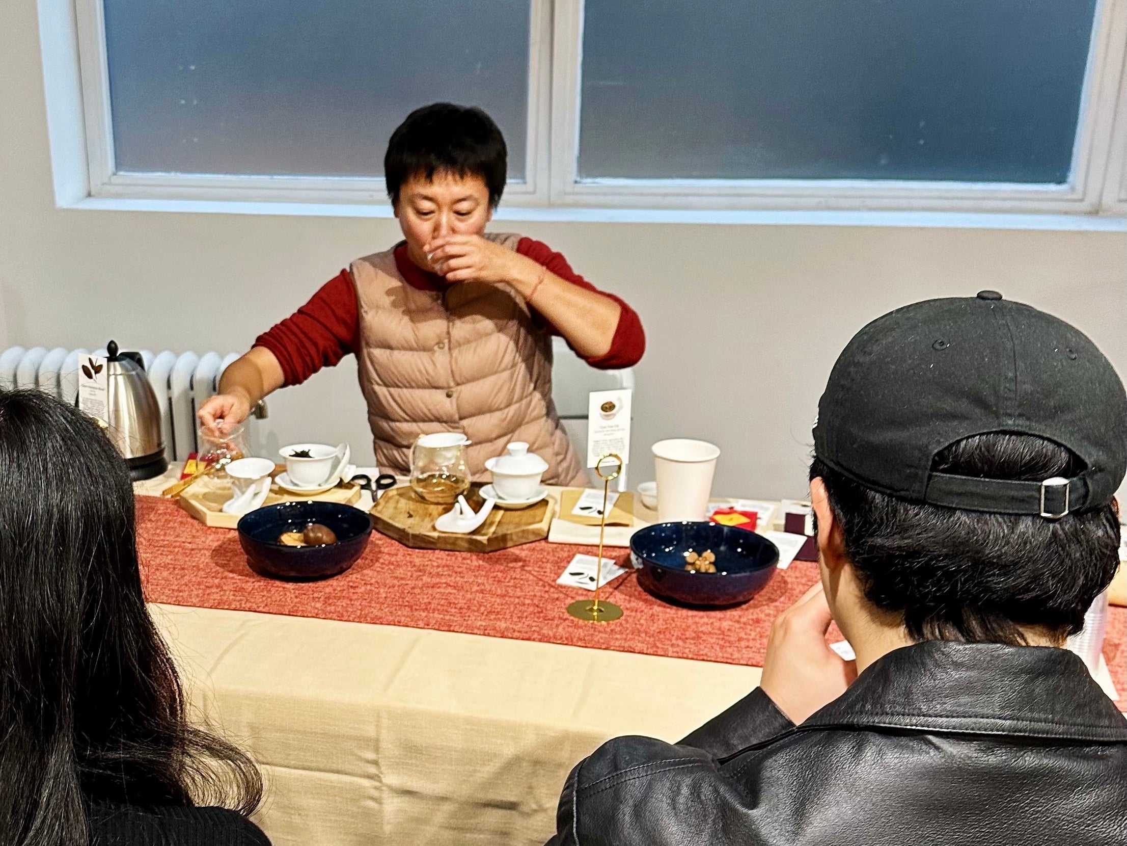 A woman smelling brewed tea from an aroma cup during a tasting demonstration.