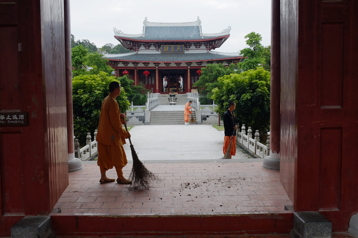 Buddhist monks sweeping the courtyard of South Shaolin Temple.