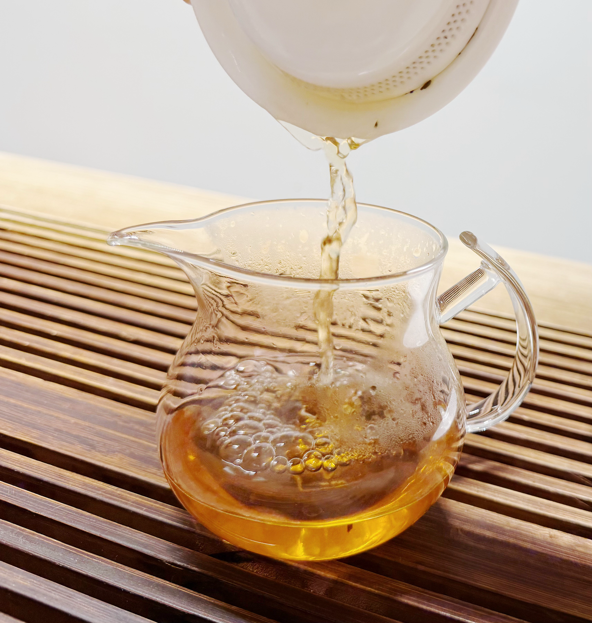 Tea being poured from a blue-and-white gai wan during brewing.