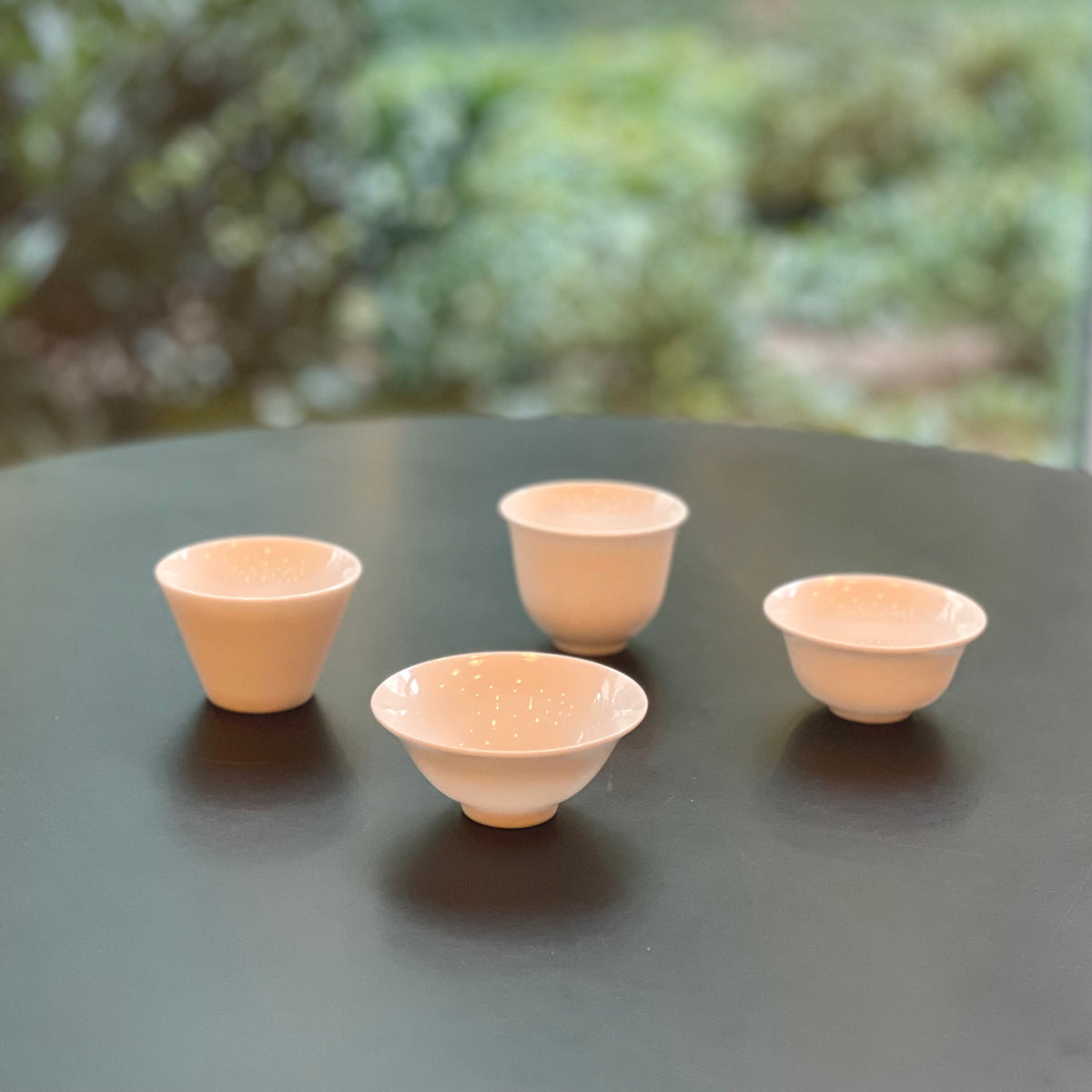 Four white porcelain teacups in different classic shapes.
