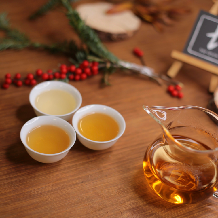 Three cups of brewed tea arranged with winter greenery and red berries.